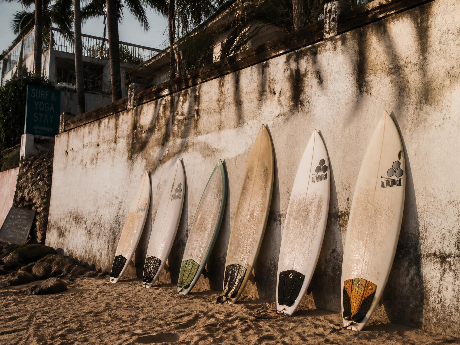 Surfboards leaning against a whitewashed wall in the afternoon sun
