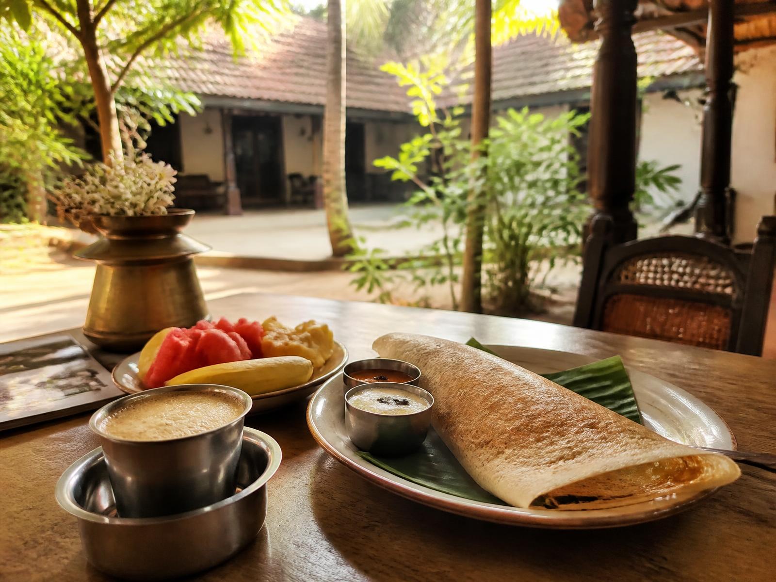 Kerala breakfast with dosa, fresh fruit and filter coffee in the courtyard