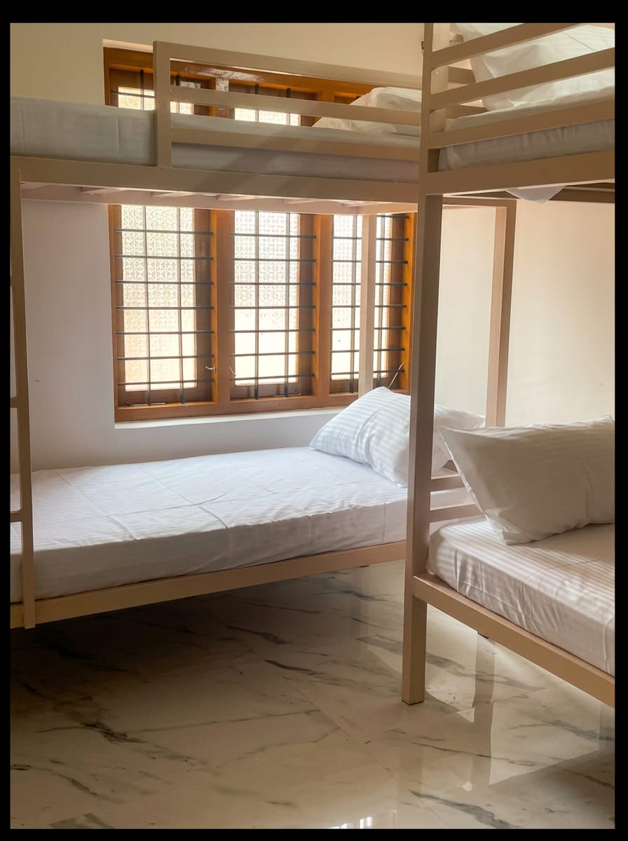 Bunk beds in the ZENWAYS dorm beside a shuttered window with crisp white linen