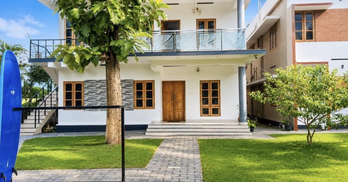 The ZENWAYS house with teak doors, balconies and a surfboard on the lawn