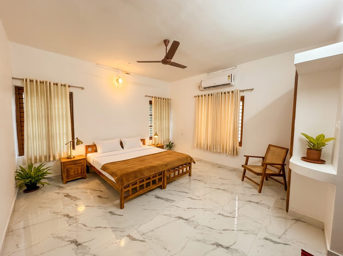 The Teak Room — king bed with teak bedside table, writing desk, chair and luggage bench in warm afternoon light