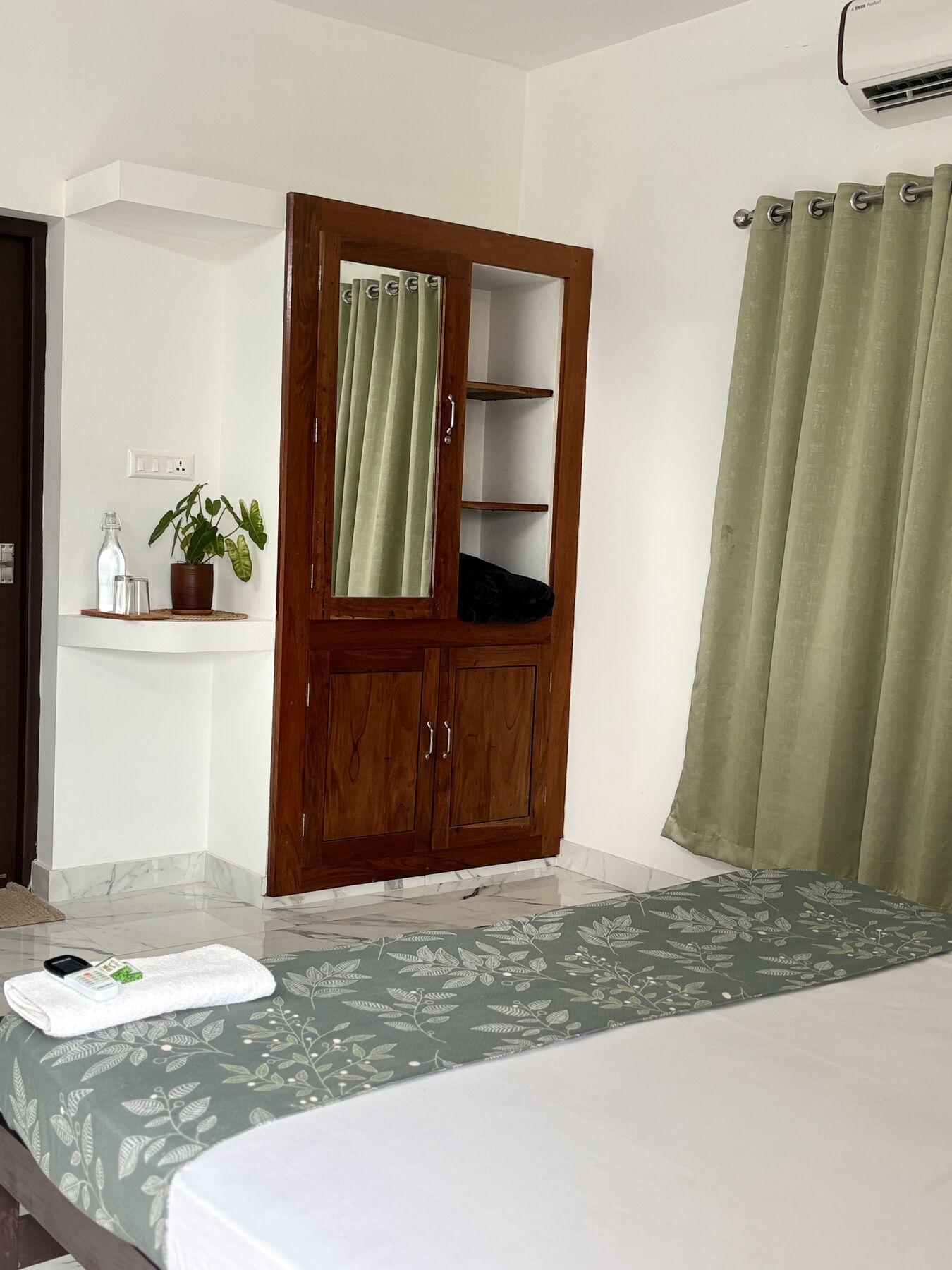 Teak wardrobe with mirror and open shelves beside sage curtains